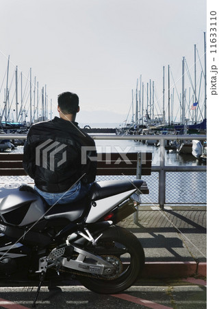 Rear view of man on motorcycle at marina 11633110