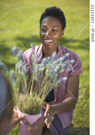 African woman reaching for potted plant 11633155