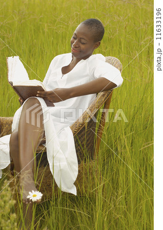 African American woman reading book outdoors 11633196