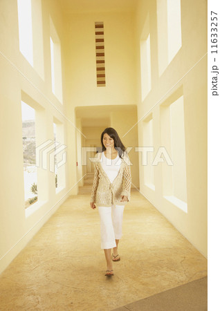 Woman walking down sunlit hallway  11633257