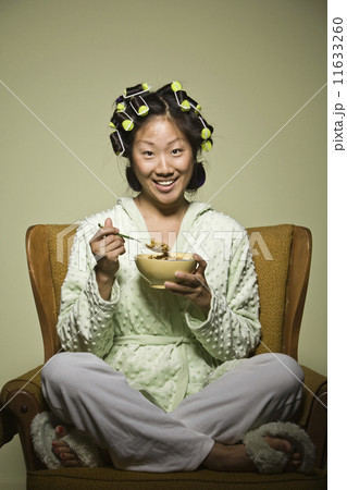 Asian woman in curlers eating cereal Asian woman in curlers eating cereal 11633260