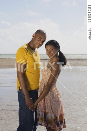 Multi-ethnic couple holding hands at beach Multi-ethnic couple holding hands at beach 11633281