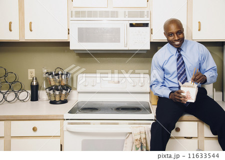 African man eating take out food in kitchen African man eating take out food in kitchen 11633544