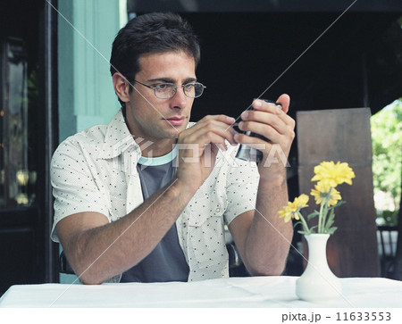 Hispanic man using electronic organizer at outdoor cafe 11633553