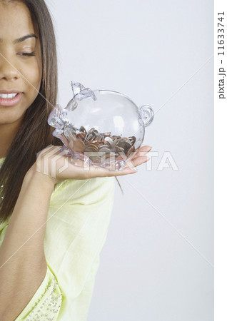 Teenage girl holding a glass piggy bank Teenage girl holding a glass piggy bank 11633741