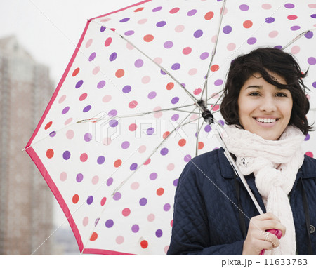 Hispanic woman walking in city with umbrella Hispanic woman walking in city with umbrella 11633783