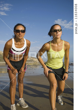 Hispanic female runners racing at beach 11634008