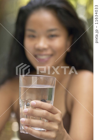 Asian woman holding glass of water Asian woman holding glass of water 11634033