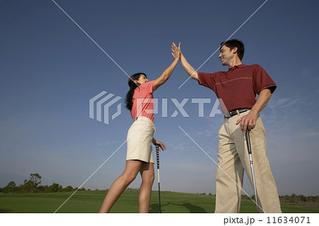 Hispanic couple high-fiving on golf course 11634071