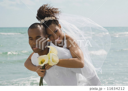 Multi-ethnic bride and groom hugging at beach 11634212