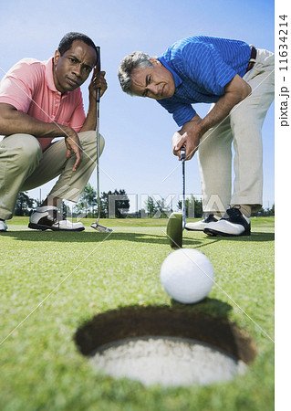 Multi-ethnic men looking at golf ball Multi-ethnic men looking at golf ball 11634214