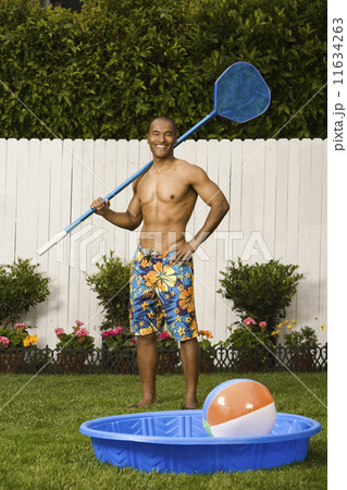 Mixed Race man holding net next to kiddie pool Mixed Race man holding net next to kiddie pool 11634263