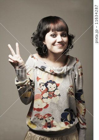 Mixed Race woman making peace sign hand gesture 11634287