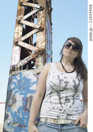 Young woman standing next to graffitied metal tower Young woman standing next to graffitied metal tower 11634408