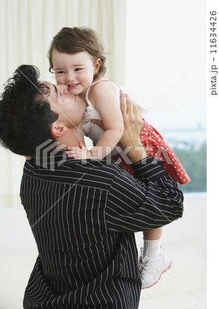 Hispanic father holding up and kissing young daughter Hispanic father holding up and kissing young daughter 11634426
