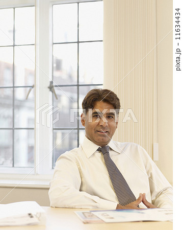 Indian businessman with paperwork at table Indian businessman with paperwork at table 11634434