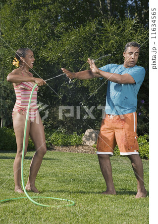 Multi-ethnic couple playing with hose Multi-ethnic couple playing with hose 11634565