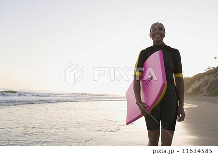 Mixed Race woman holding body board 11634585