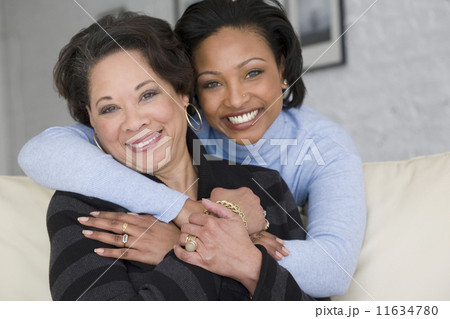 African mother and adult daughter hugging 11634780