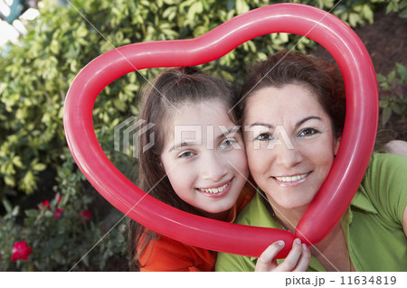 Hispanic mother and daughter holding heart-shaped balloon 11634819