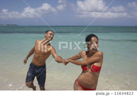 Hispanic woman pulling boyfriend at beach Hispanic woman pulling boyfriend at beach 11634822