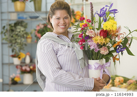Hispanic woman holding flowers in vase 11634993