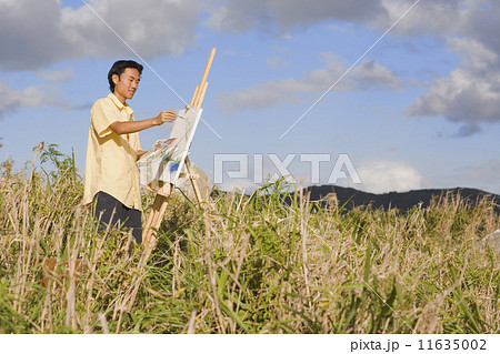Asian man painting at easel outdoors Asian man painting at easel outdoors 11635002