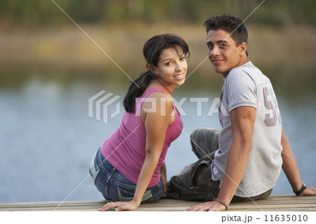 Multi-ethnic couple sitting on dock 11635010