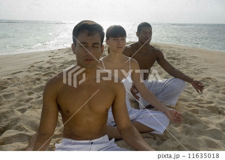 Multi-ethnic friends meditating on beach 11635018