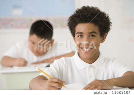 Hispanic boy writing at school desk 11635104