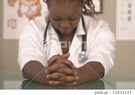 African female doctor with head down at desk 11635141