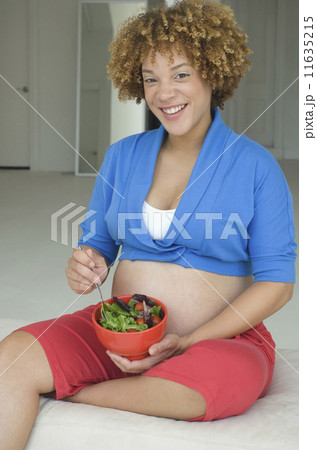 Pregnant African woman eating salad Pregnant African woman eating salad 11635215