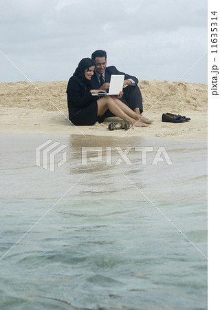 Hispanic businesspeople working at beach Hispanic businesspeople working at beach 11635314