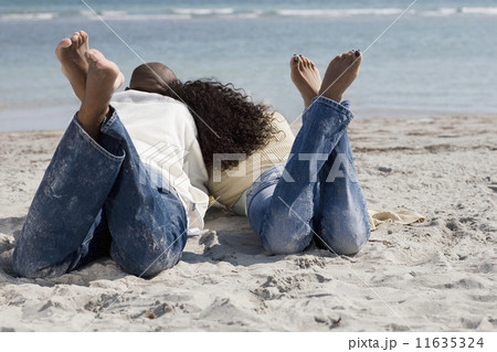 Multi-ethnic couple laying on beach 11635324