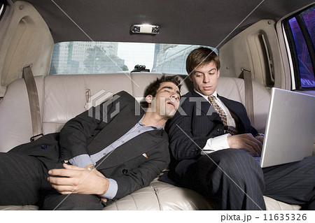 Hispanic businessman sleeping on coworker in limousine 11635326