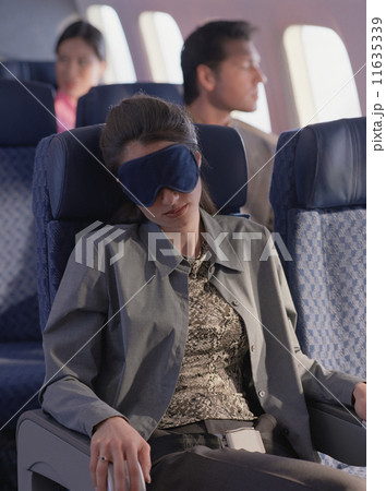 Young woman sleeping on airplane with eye mask 11635339