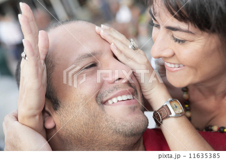 Hispanic woman covering husband's eyes 11635385