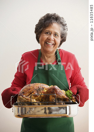 Senior Hispanic woman holding roasted turkey 11635485