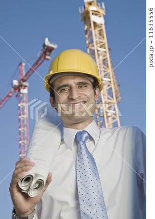 Hispanic businessman holding blueprints 11635556