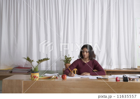 Indian female teacher writing at desk 11635557