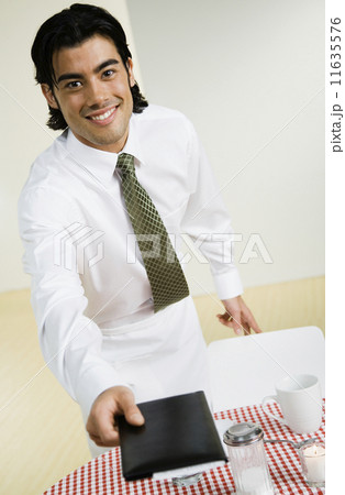 Mixed Race waiter handing over bill 11635576