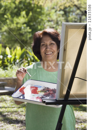 Senior Hispanic woman painting with easel outdoors 11635586