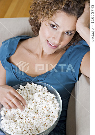 Hispanic woman eating popcorn on sofa Hispanic woman eating popcorn on sofa 11635745