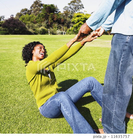 African man helping girlfriend up off grass 11635757