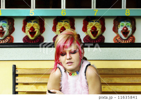 Young Hispanic punk female sitting in front of carnival booth 11635841