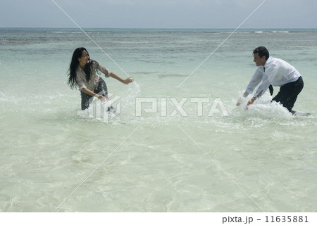 Hispanic businesspeople playing in water 11635881