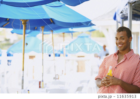 Hispanic man with drink at beach Hispanic man with drink at beach 11635913