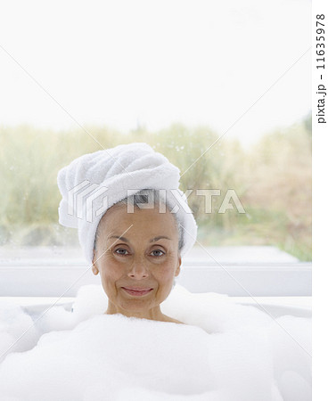 Portrait of elderly woman in bubble bath with towel wrapped around head Portrait of elderly woman in bubble bath with towel wrapped around head 11635978