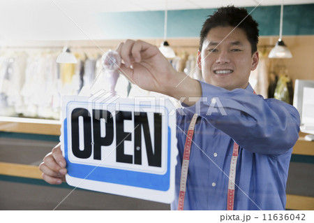 Asian drycleaner putting up open sign Asian drycleaner putting up open sign 11636042
