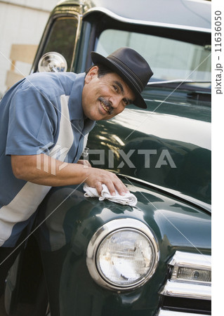 Middle-aged Hispanic man waxing classic car 11636050
